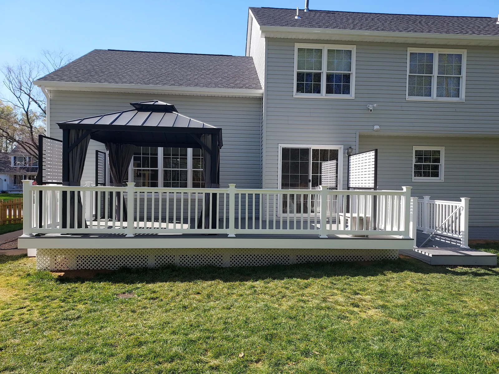 Backyard deck with white railings, lattice, steps to the yard, and space for outdoor seating.